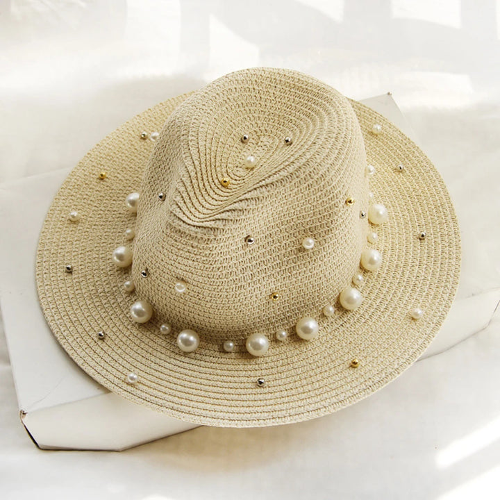 Elegant straw hat with pearl trim on display stand against neutral background