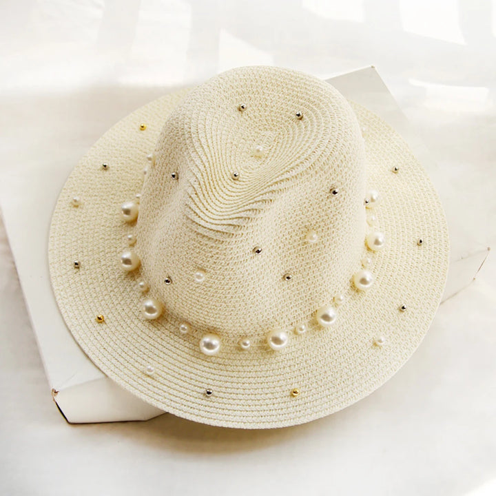 Elegant straw hat with pearl trim on display stand against neutral background