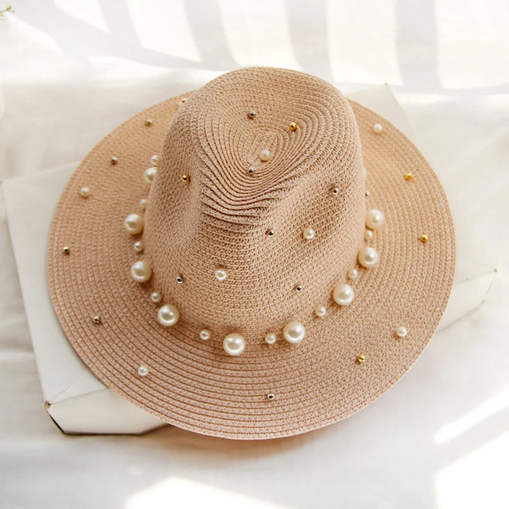 Elegant straw hat with pearl trim on display stand against neutral background