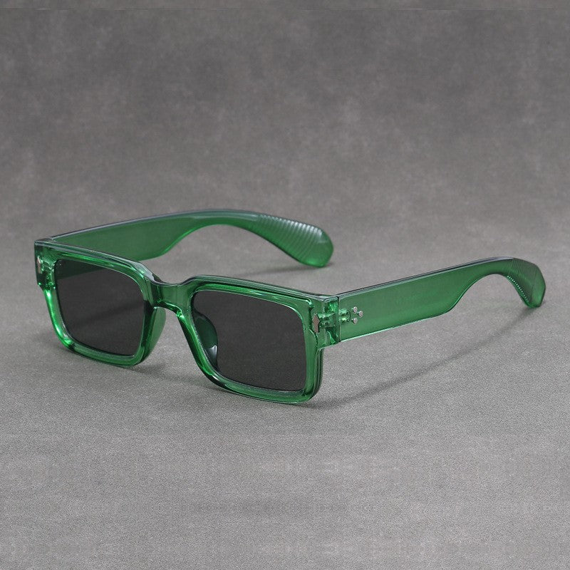 Green sunglasses with black lenses on a gray background