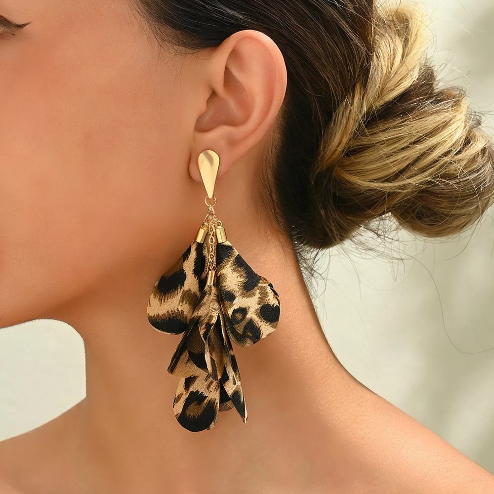 A person wearing leopard cascading petal-like earrings with a gold-tone teardrop post.