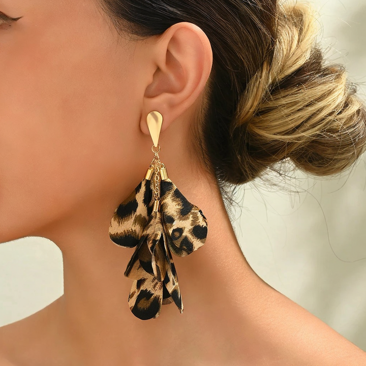 A person wearing leopard cascading petal-like earrings with a gold-tone teardrop post.