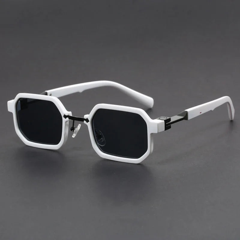 A pair of sunglasses with a unique octagonal frame, predominantly white with black lenses, displayed against a grey background.
