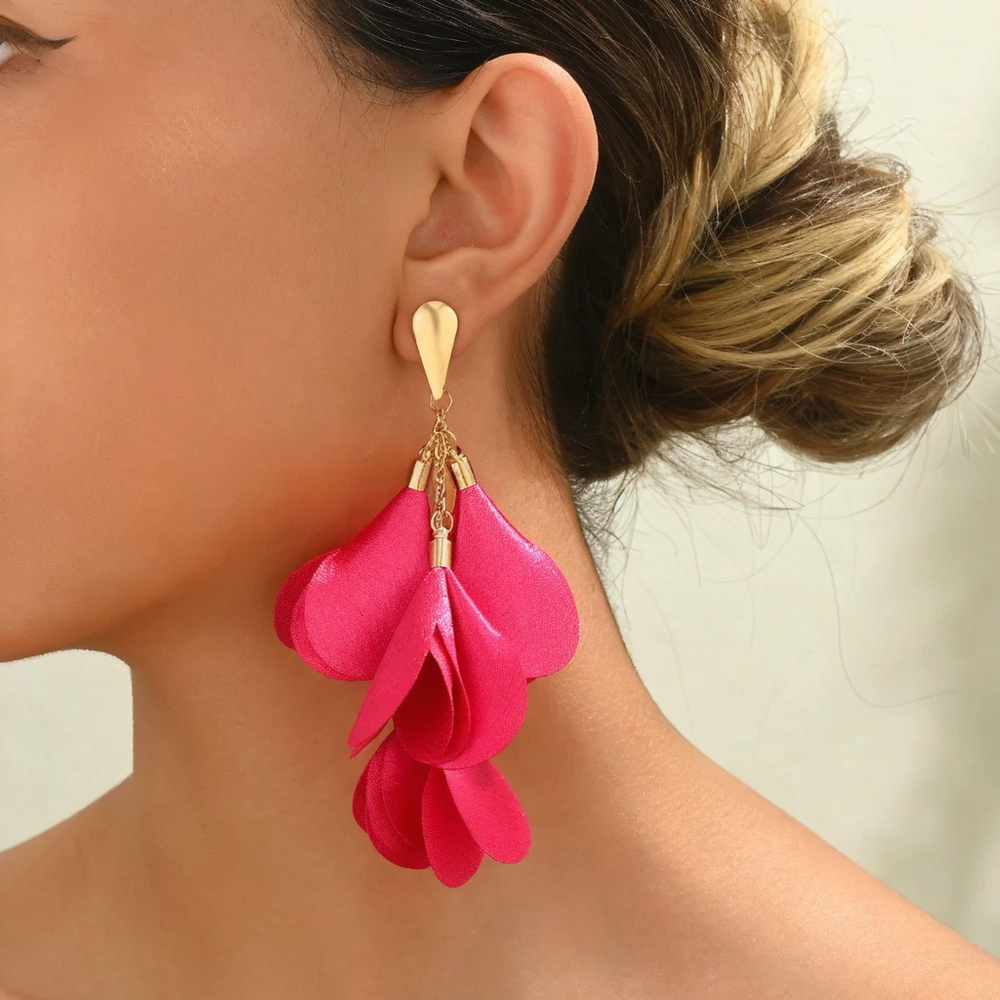 A person wearing pink cascading petal-like earrings with a gold-tone teardrop post.