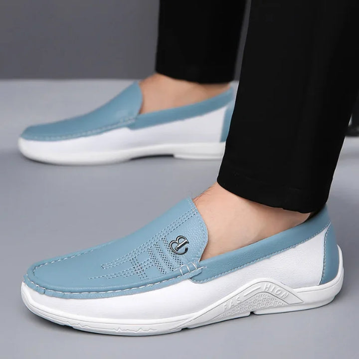Blue and white loafers worn with black pants on a gray background