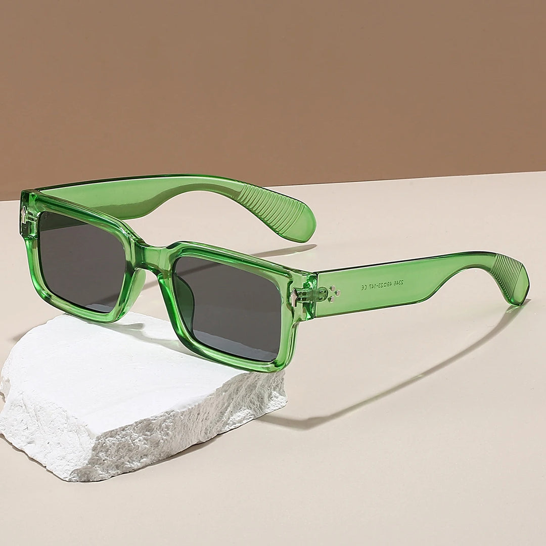 A pair of square-framed sunglasses with a green frame on a white rock