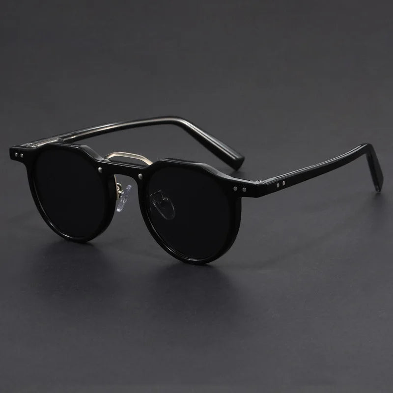 A pair of round-framed sunglasses with clear browline design and black frames.