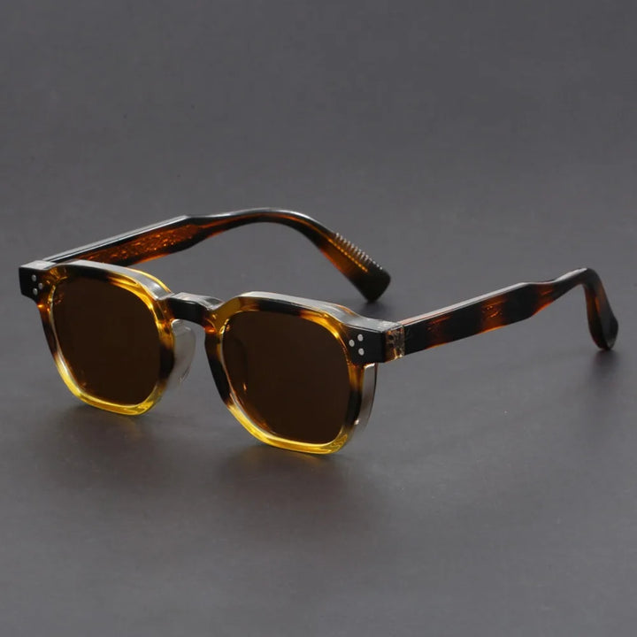 A pair of square-framed sunglasses with studded temples, featuring a patterned frame design and tinted lenses.