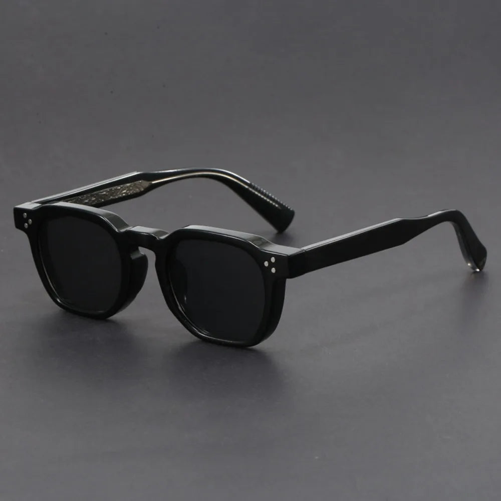 A pair of square-framed sunglasses with studded temples, featuring a patterned frame design and tinted lenses.
