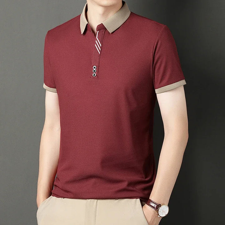 Maroon polo shirt with beige collar and trim on a gray background