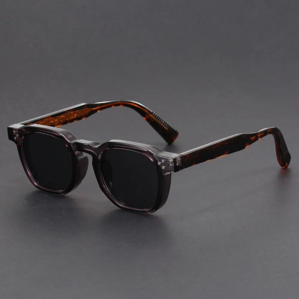 A pair of square-framed sunglasses with studded temples, featuring a patterned frame design and tinted lenses.