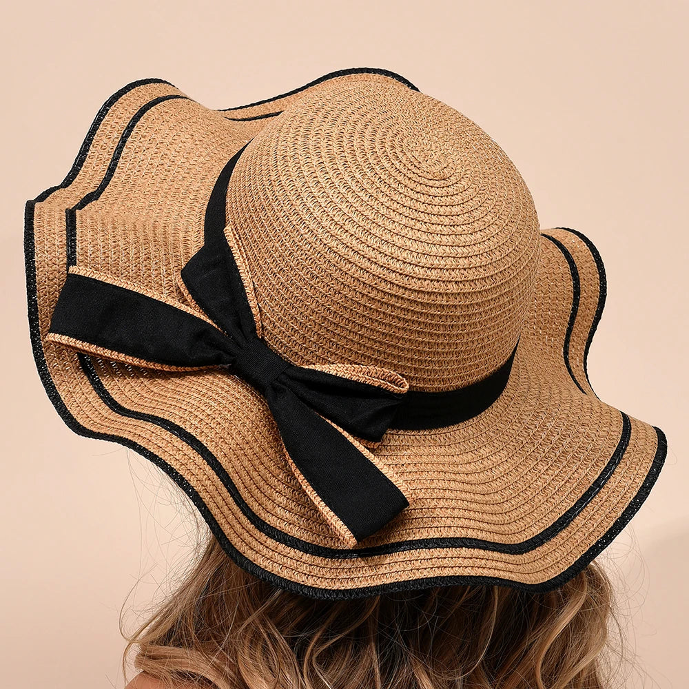 Beige straw hat with black ribbon on a beige background