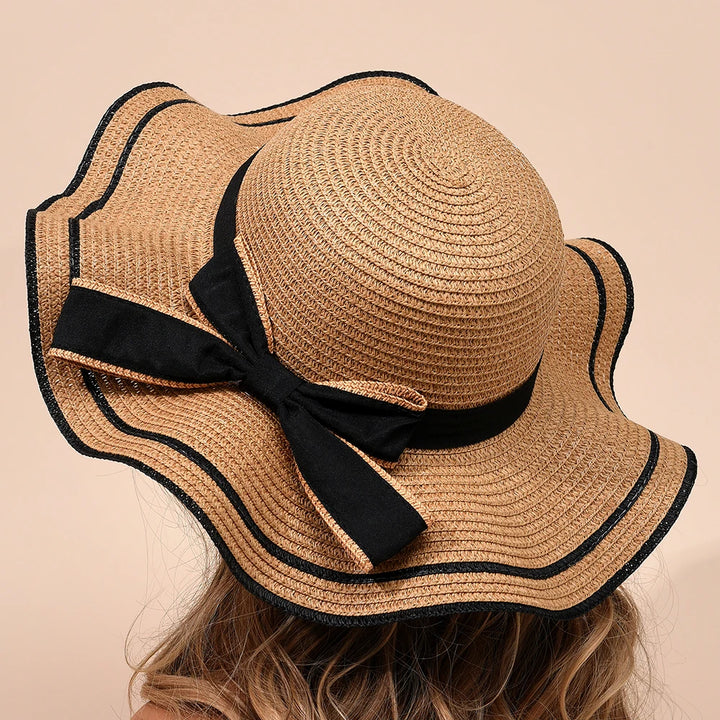 Beige straw hat with black ribbon on a beige background